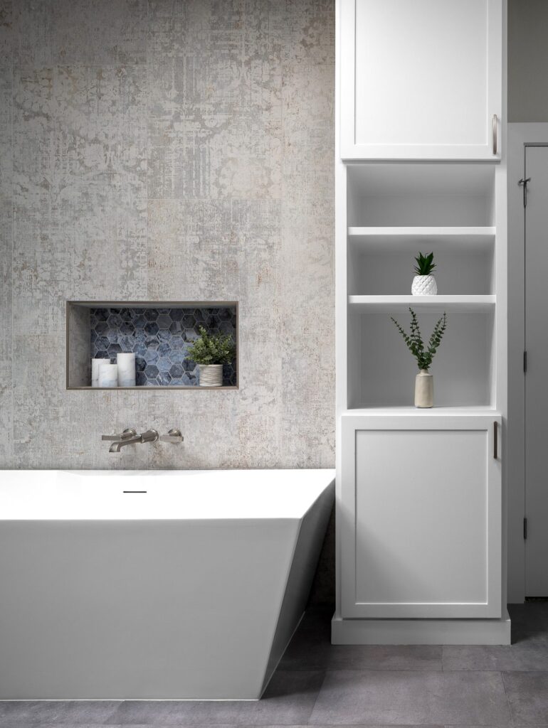 Freestanding tub with blue hexagon tile niche and built-in linen storage