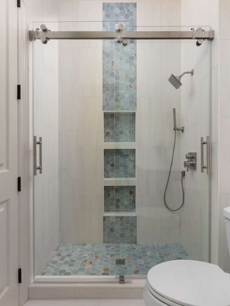 Guest bath shower with glass slider and blue mosaic accent stripe
