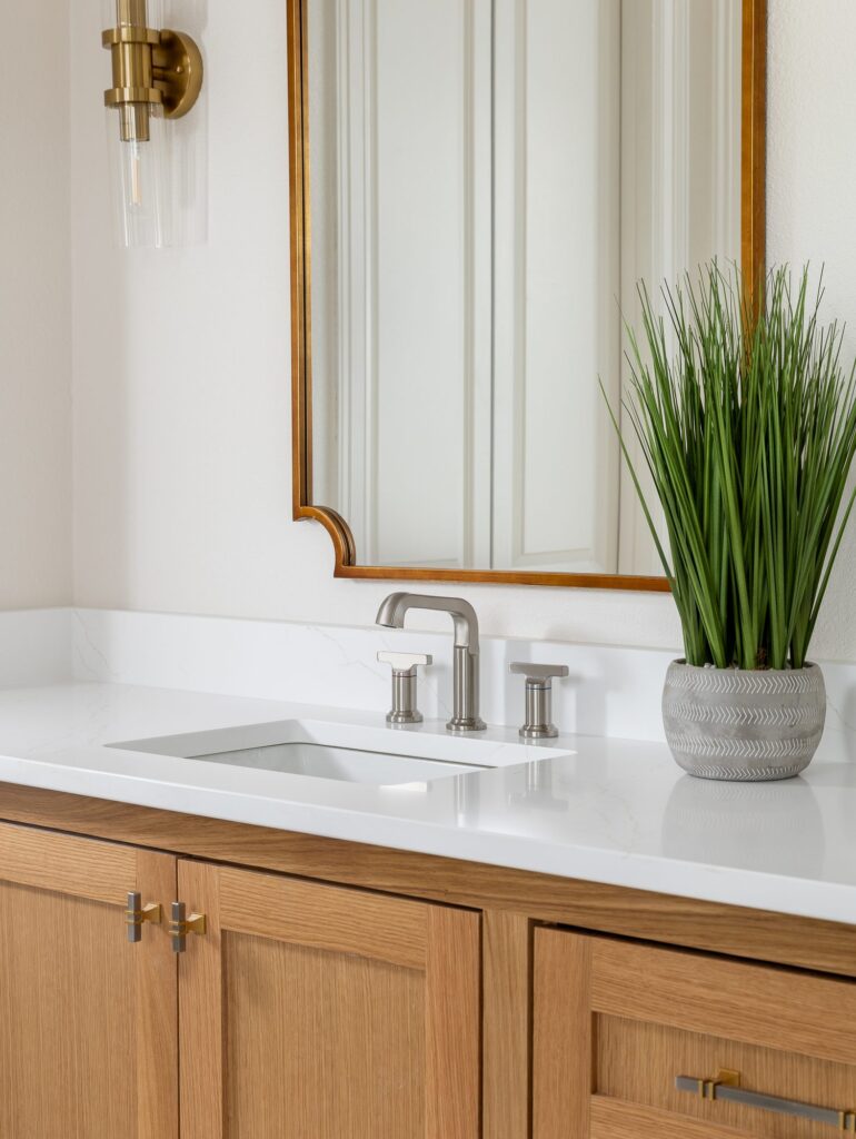 Quartz vanity top, brushed nickel faucet and brass mirror detail in a primary bathroom