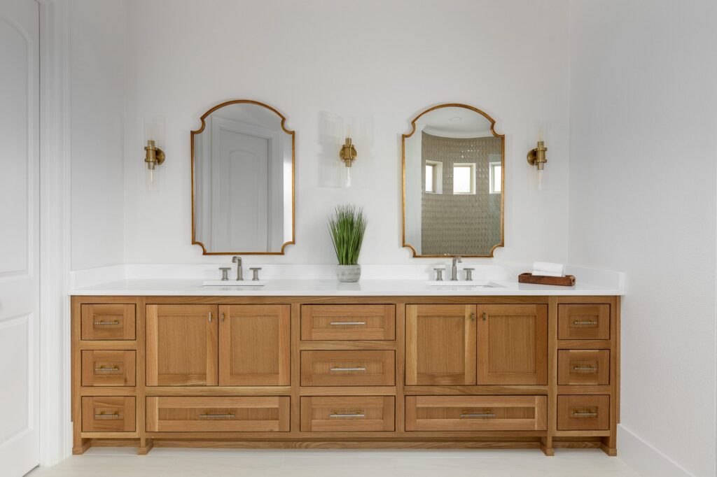 White oak double vanity with brass mirrors in a primary bath remodel in Argyle, Texas