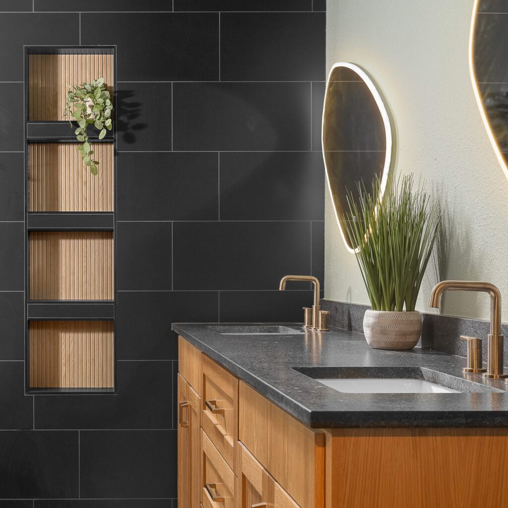 Charcoal tile primary bath with lit display niches, backlit mirror and wood vanity