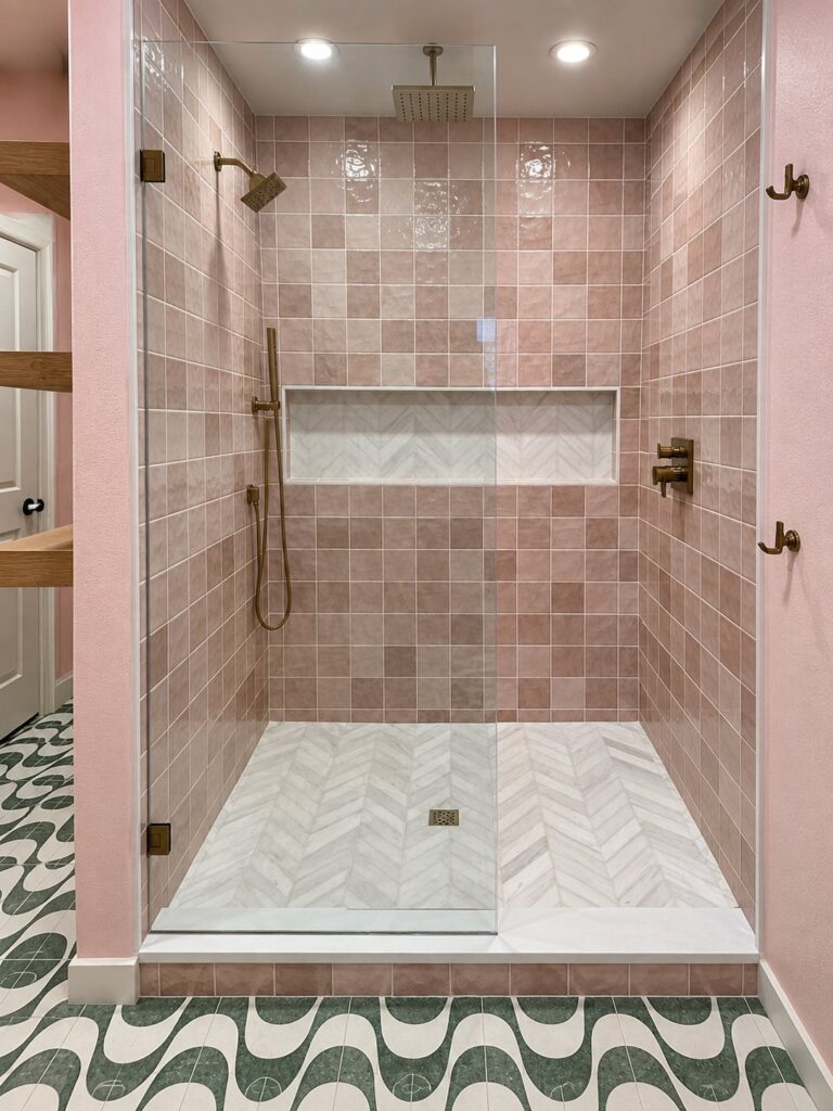 Walk-in shower with blush tile, niche and herringbone floor in a Southlake home