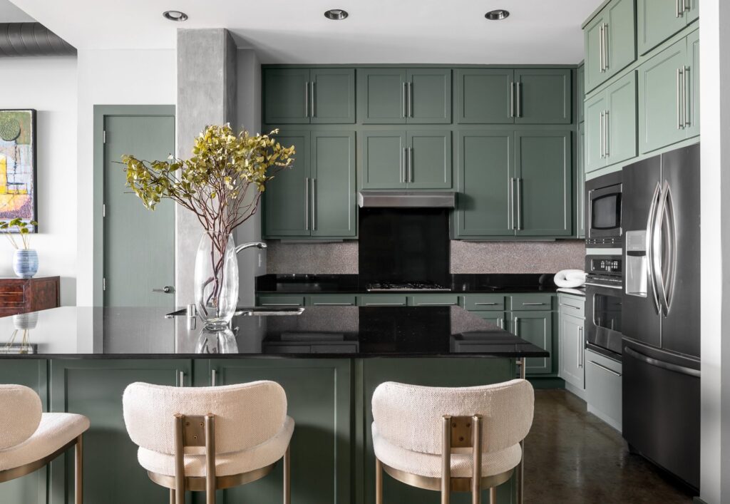 Sage green custom cabinetry and dark island in a remodeled Dallas condo kitchen